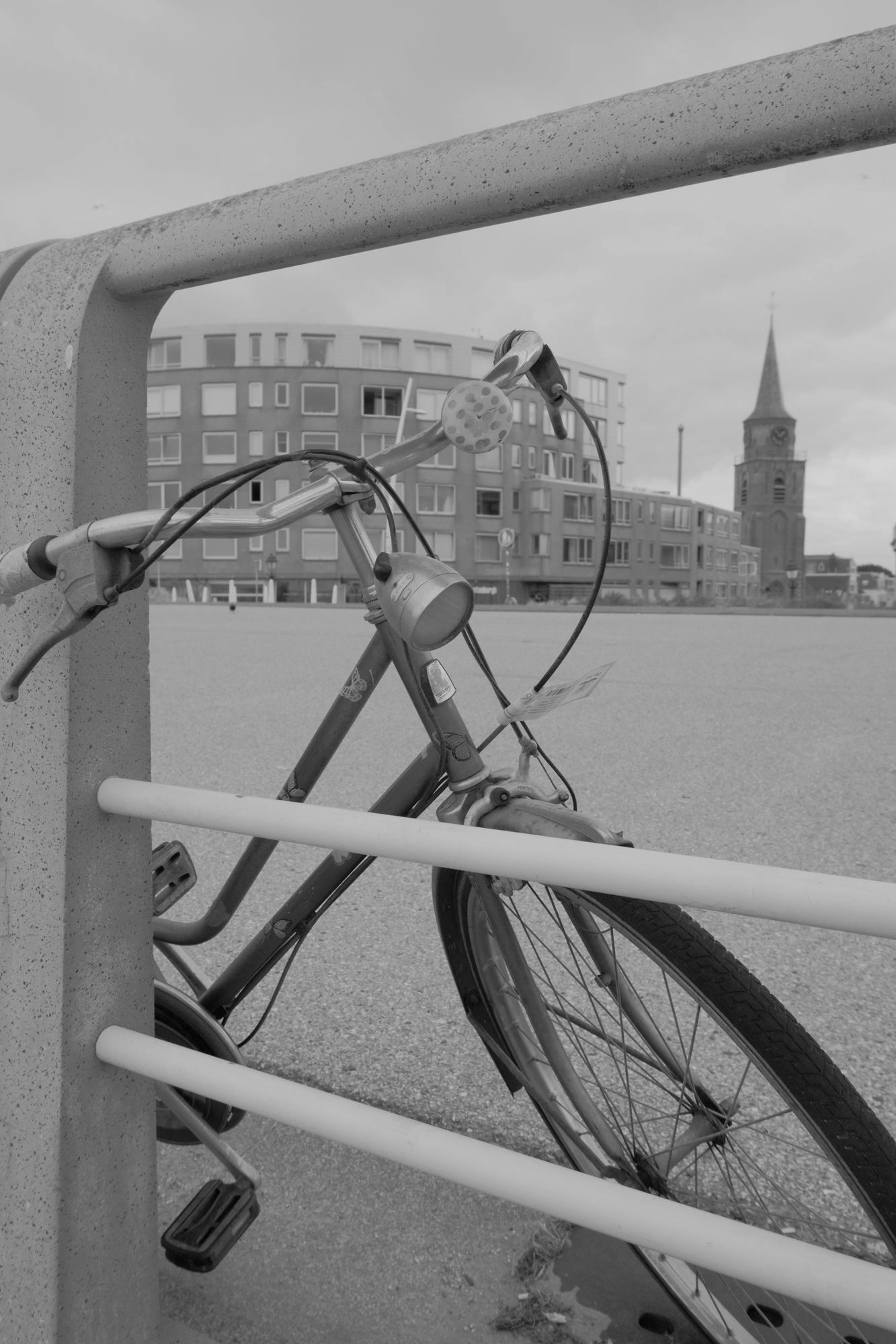 2026-07-18 - xt15-45 - bw - NL - Scheveningen - Bike parked next to fence with church in background