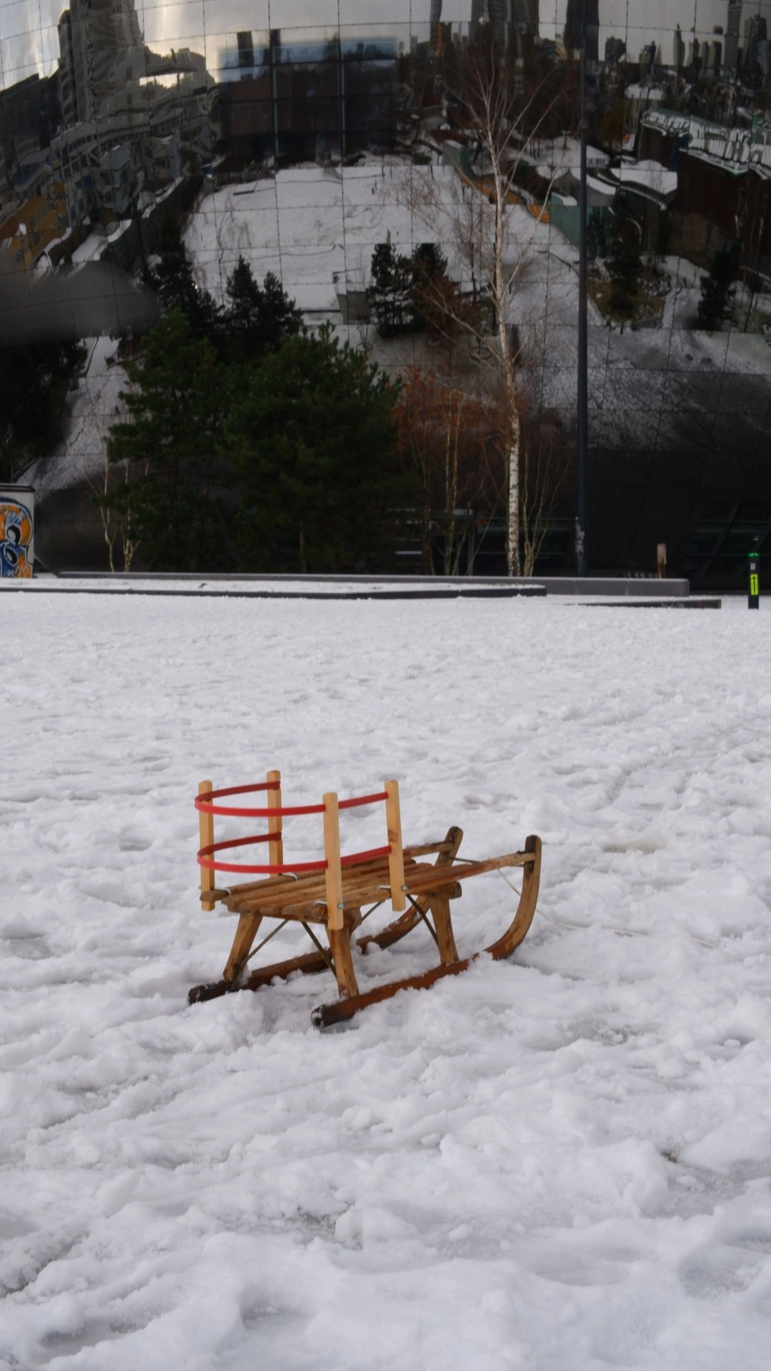 2026-01-04 - xt35 - color - NL - Rotterdam - Sled on the snow in front of large mirror-covered building