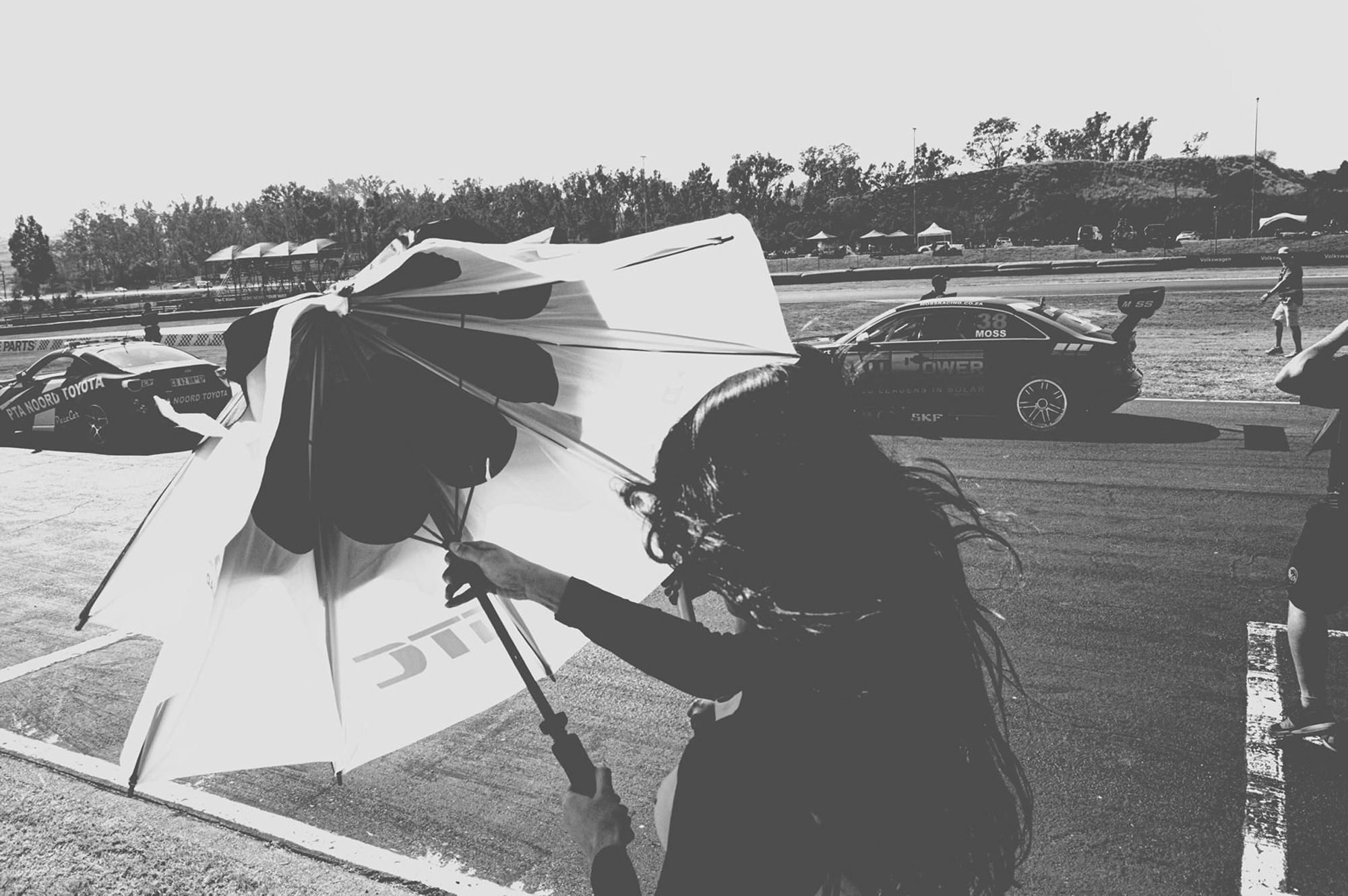 2019-07-27 - n18-55 - bw - ZA - Zwartkops Raceway - Person with umbrella walks across track