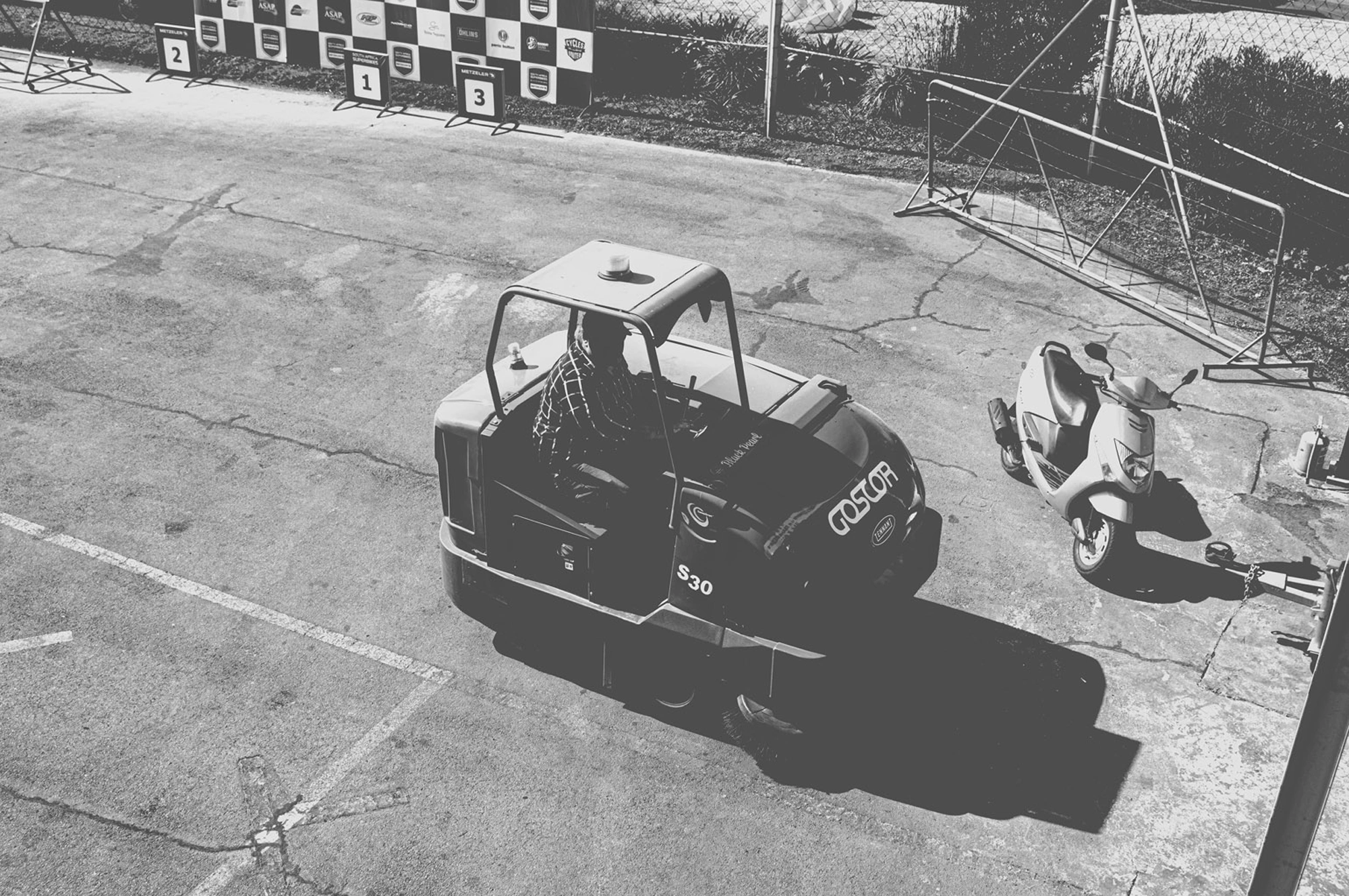 2019-07-27 - n18-55 - bw - ZA - Zwartkops Raceway - Track clearing machine beside scooter